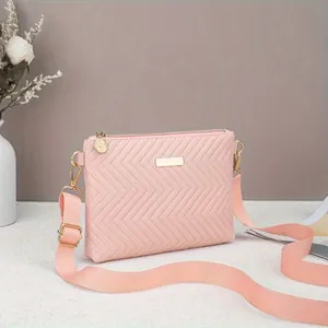 Close-up detail of pink chevron quilted texture and elegant gold plaque on crossbody bag.