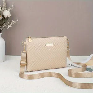 Detail view of a beige chevron quilted crossbody bag with elegant gold hardware accents