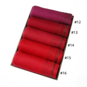 Detail view of jersey diamond scarves in gradient red tones with rhinestone edges