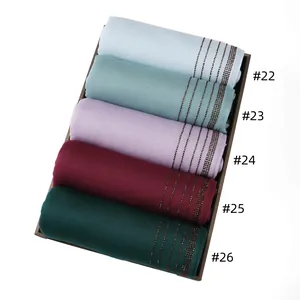 Close-up of multicolored jersey diamond scarves with rhinestone details in a tray