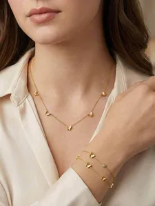 Parure collier et bracelet papillon dorés portés par une femme élégante et raffinée