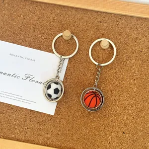 Rotating basketball and soccer ball metal sports keychains set on a cork background