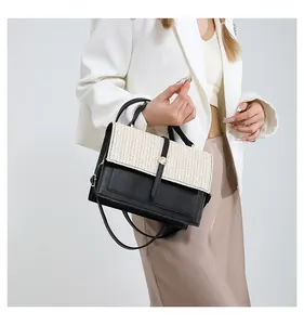 Close-up of an elegant black and woven cream color-block crossbody bag for women