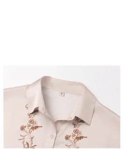 Close-up of elegant satin pajama top with floral embroidery and collar detail.