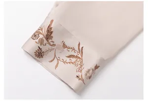 Close-up detail of the elegant floral print on a champagne satin pajama sleeve cuff