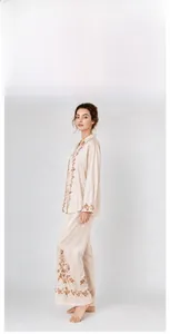 Elegant woman in beige satin pajama set featuring intricate floral embroidery detail