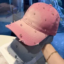Detailed view of pink baseball cap featuring pearl embellishments and distressed edges