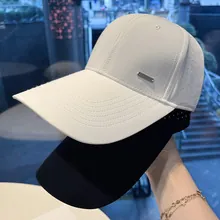 Close-up view of breathable white and black baseball caps featuring metal logo detail