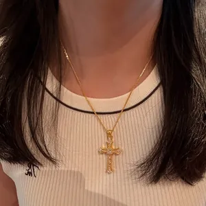 Elegant gold cross pendant necklace with sparkling stone inlay worn by model