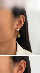 Detailed view of two-tone gold and silver rectangular earrings on a model's ear