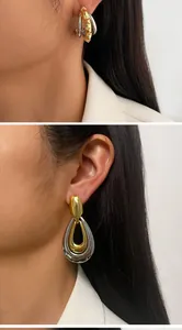 Close-up detail of oversized two-tone mixed metal gold and silver earrings on model.