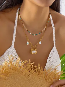 Primer plano detallado de un collar bohemio dorado de doble capa con colgante de cangrejo