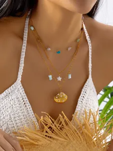 Detalle exquisito de un collar bohemio dorado con capas y dijes de concha y estrella