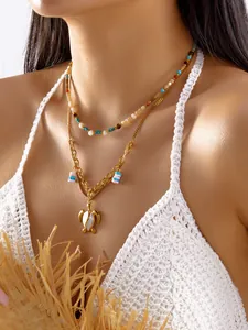 Detalle de un conjunto de collares dorados a capas con colgante de tortuga marina
