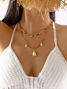 Detalle de un collar bohemio dorado de varias capas con colgante de tortuga marina.