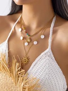 Primer plano de collar bohemio dorado con colgante de sol y conchas marinas en modelo