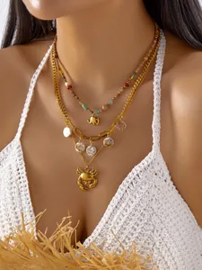 Primer plano de un collar dorado bohemio de varias capas con colgantes de cangrejo y elefante