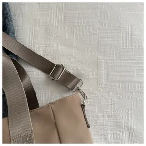 Close-up detail of the adjustable nylon strap and metal hardware on a khaki tote bag