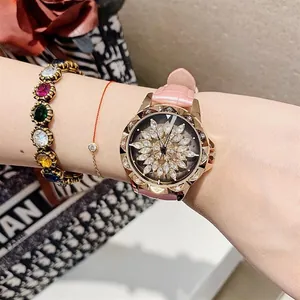 Macro view of pink leather strap watch with rotating crystal flower dial and gold bracelets