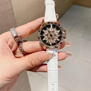 Close-up of rotating floral rhinestone dial on a white leather strap women's watch