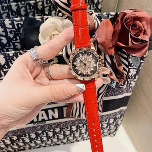 Detail of red leather watch strap and crystal flower dial on a stylish gold bezel watch