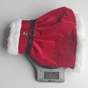 Close-up of a red velvet Christmas skirt wine bottle cover being weighed on a digital scale