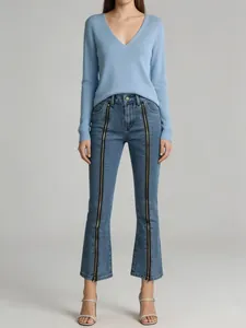 Full view of fashionable women's flare jeans with dual front zippers and blue sweater