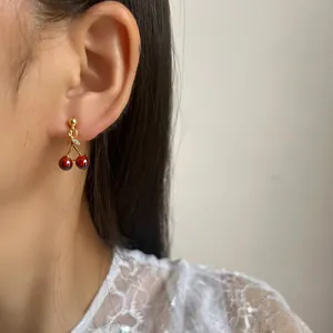 Vibrant pomegranate red cherry drop earrings featured on model for unpierced ears
