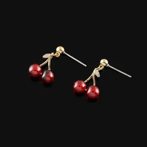 Pomegranate red cherry stud earrings with gold stems on black reflective background