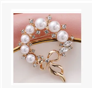 Elegant golden pearl wreath brooch featuring a delicate bow and sparkling crystals