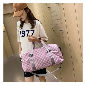 Large pink checkerboard travel duffle bag for sports or travel held by model outdoors