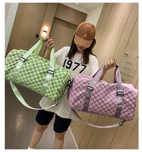 Model carrying two large capacity checkered travel duffel bags in green and pink colors