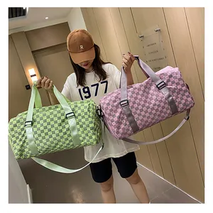 Close-up of checkered green and pink duffel bags held by a model in a stylish indoor setting