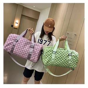 Fashionable model holding pink and green checkerboard duffle bags in a modern interior