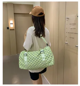 Back view of a model carrying a green checkerboard pattern large travel duffel bag