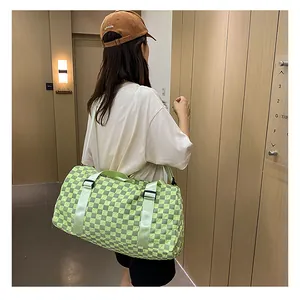 Side view of a large lime green checkered travel duffle bag carried by a woman