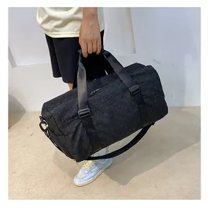 Large capacity black travel duffel bag with elegant monogram pattern held by a person in hand