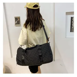 Stylish woman wearing a yellow cap carrying a large black checkered travel duffel bag
