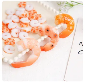 Macro shot of realistic PVC shrimp tail pendants and orange striped beads for DIY crafts