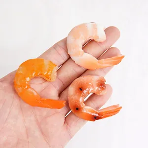 Realistic PVC shrimp food models in orange and pink shown in hand for size scaling