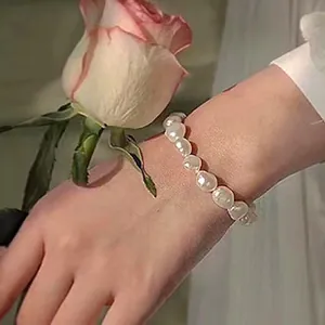 Gros plan d'un bracelet en perles d'eau douce baroques naturelles porté au poignet avec rose.