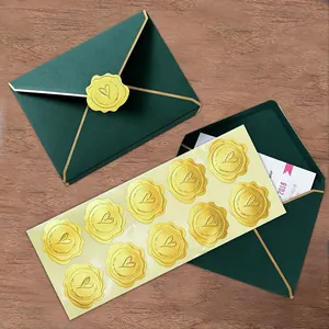 Close-up detail of golden heart wax seal stickers on a sheet and a green gift envelope.