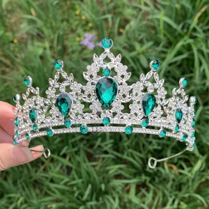 Detailed shot of vintage silver bridal tiara with green emerald stones on grass