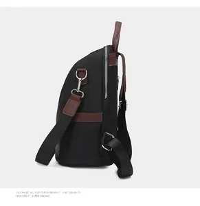 Detail of multi-functional black backpack showing side leather straps and metal zippers