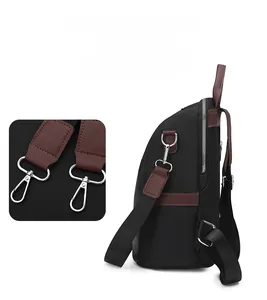 Detail of detachable silver metal hook and brown faux leather trim on black backpack