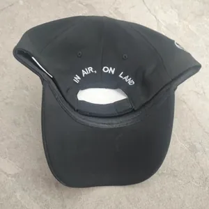 Detail of black baseball cap with In Air On Land white embroidery on the back