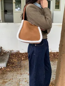 Detail of a brown suede handbag with white faux shearling trim and slim leather strap