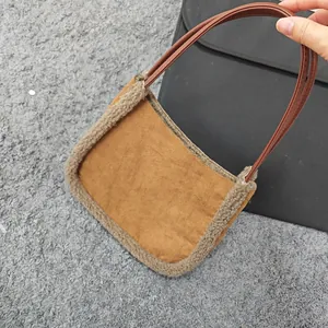 Detail of faux suede handbag with plush shearling trim and slim brown handles