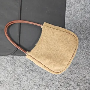 Detail of beige fleece shoulder bag showing brown trim and leather strap texture