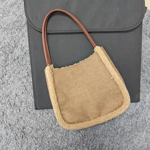 Detail of a brown lamb wool tote bag with soft plush trim on a gray carpet background